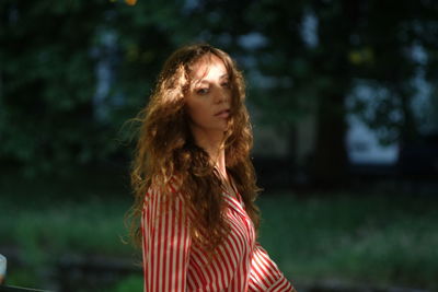 Portrait of beautiful woman with tousled hair standing in park