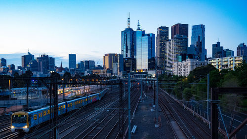 Railroad tracks amidst buildings in city against sky