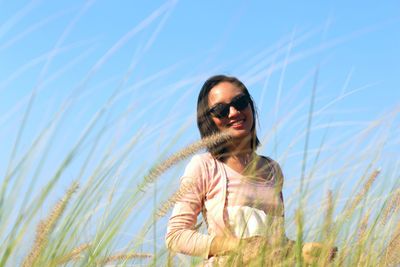 Portrait of smiling young woman standing amidst grass