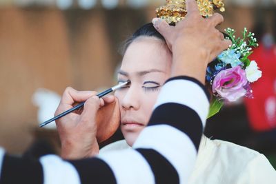 Cropped image of artist applying make-up on young woman