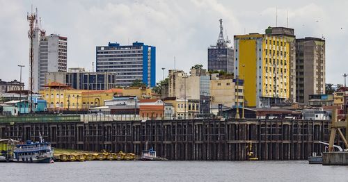 Buildings by river against sky in city