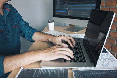 Midsection of man using laptop on table