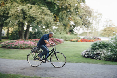 Full length side view of senior man riding bicycle in park