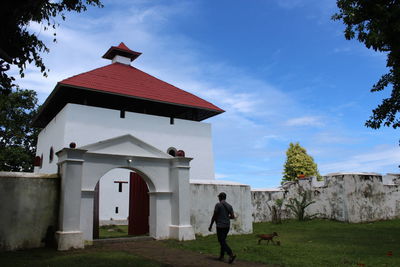 Woman standing by building against sky