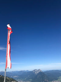 Red flag against mountain range against clear blue sky