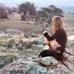 Rear view of woman sitting on rock