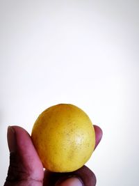 Close-up of hand holding apple against white background