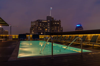 Illuminated buildings by swimming pool at night