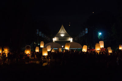 Crowd at illuminated city against sky at night