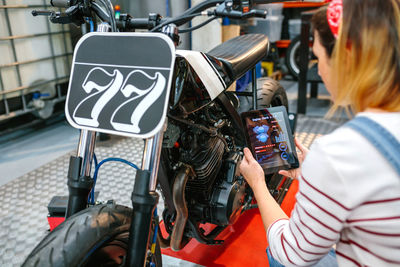 Mechanic woman using diagnosis app to review custom motorcycle