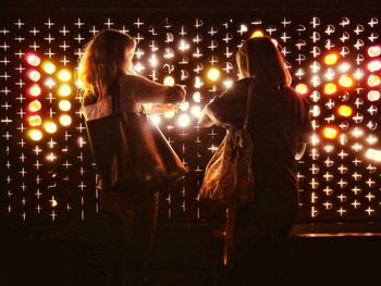Rear view of women standing at night