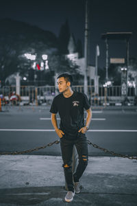 Portrait of young man standing on road in city