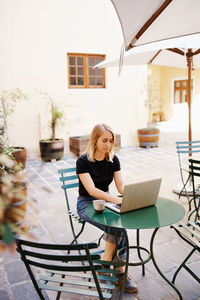 Young woman using laptop while sitting on chair