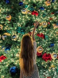 Rear view of woman decorating christmas tree
