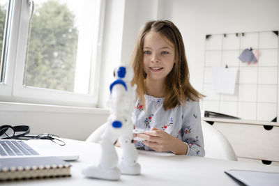 Portrait of a smiling girl sitting on table