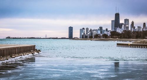 Sea by city against sky