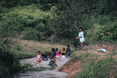 People on riverbank in forest