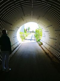 Rear view of people walking in tunnel