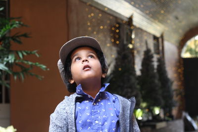 Boy wearing hat looking up while standing outdoors