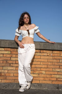 Young woman standing against wall