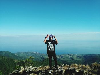 Rear view of man photographing on mountain against sky