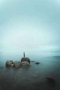 A person standing on the rock at the middle of the lake captured with long exposure