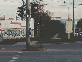 Road sign on street in city against sky