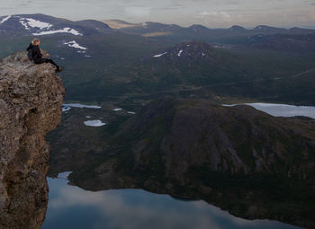 Side view of woman sitting on cliff