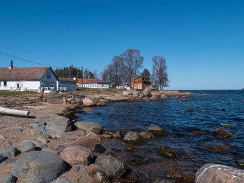 Sea by houses against clear blue sky