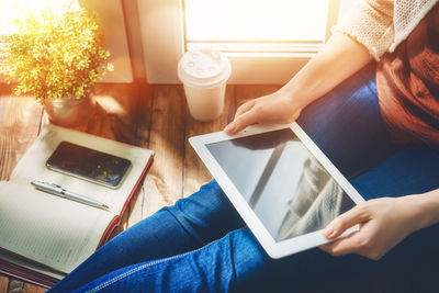 Woman person working on the tablet while sitting at the window.