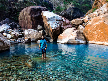 Rear view of man walking on rock by waterfall