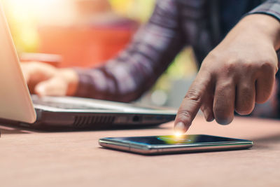 Midsection of man using mobile phone on table