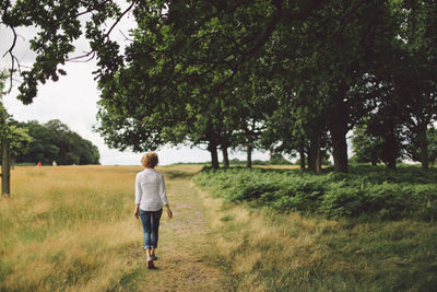 Full length rear view of young woman walking on footpath