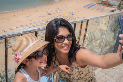 High angle view of smiling woman taking selfie with daughter at beach