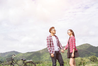 Young couple standing on mountain against sky
