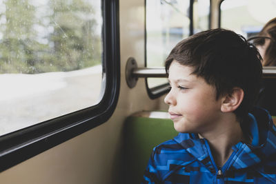 Boy looking away through window while sitting in bus