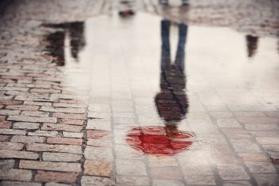 Low section of man with reflection on puddle