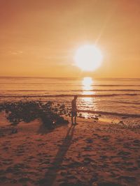 Man standing at beach against sky during sunset