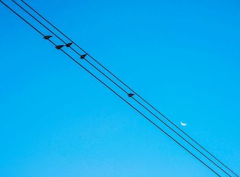 Low angle view of crane against clear blue sky