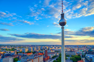 Communications tower in city against sky