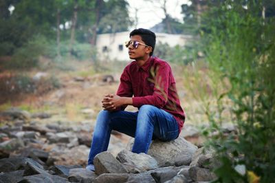 Full length of young man sitting on rock