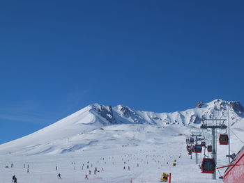 People on snowcapped mountain against blue sky