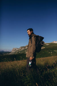 Full length of man standing on field against clear sky