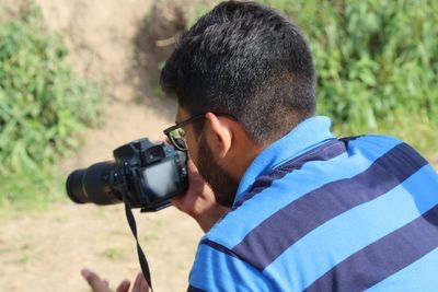 Rear view of man photographing with camera on field