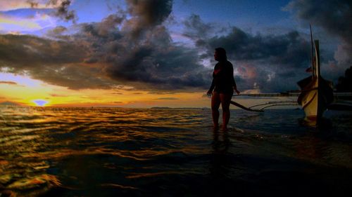 Rear view of silhouette man standing at beach against sky