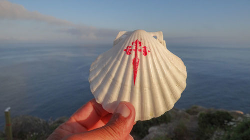 Close-up of hand holding umbrella against sea