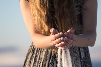 Midsection of woman holding hands against sky