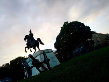 Silhouette man riding horse statue against sky