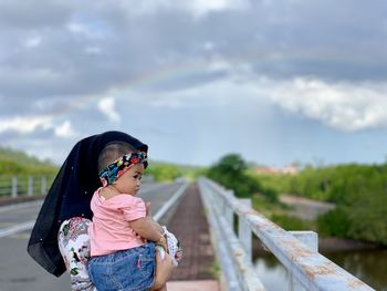 Side view of girl standing against sky