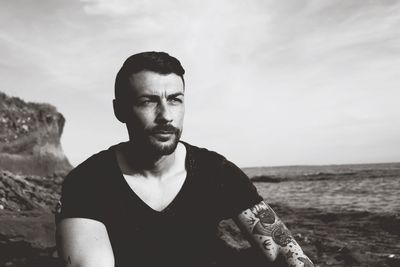 Man sitting on rock against sea at beach